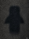Affiche minimaliste noire : une ombre de voiture vue de dessus, floue et sombre, projetée sur un bitume gris granuleux, sans la voiture elle-même